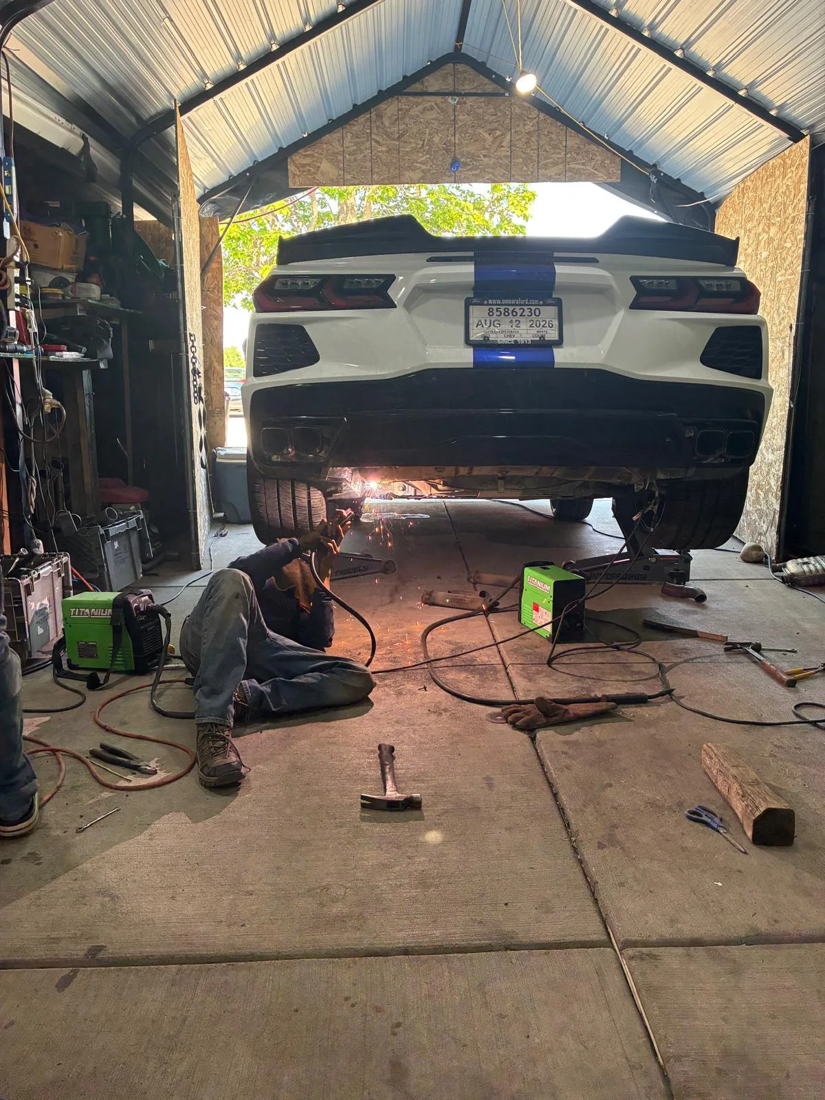 Welding a custom exhaust system under a Chevrolet Corvette in Denver