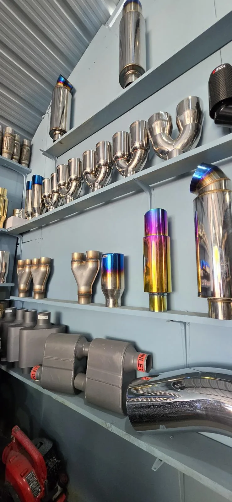 Wall of custom exhaust tips and mufflers at Poncho Welding